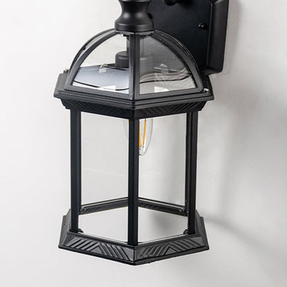 Closeup view of lantern wall light with clear glass panels and decorative metal frame.