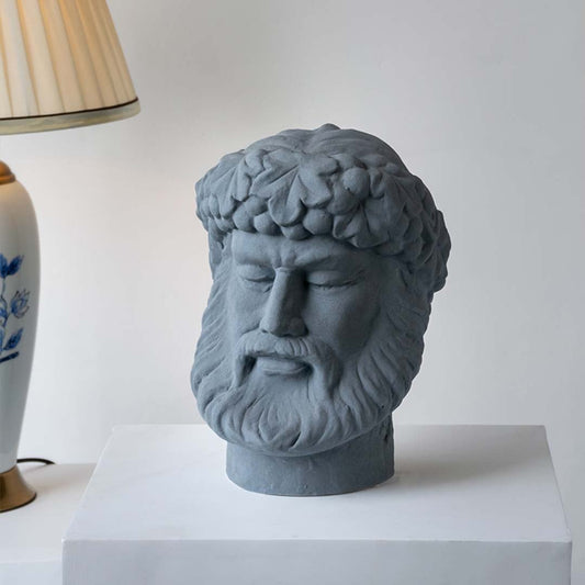 Gray stone sculpture head displayed on a simple table adding an artistic décor accent that enhances interior styling with sculptural charm and refined detail.