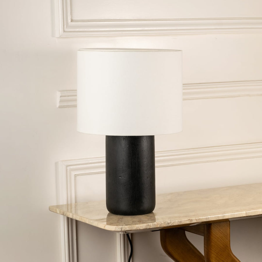 Black ceramic table lamp with cylindrical textured base and white fabric shade for modern interior decor styling.