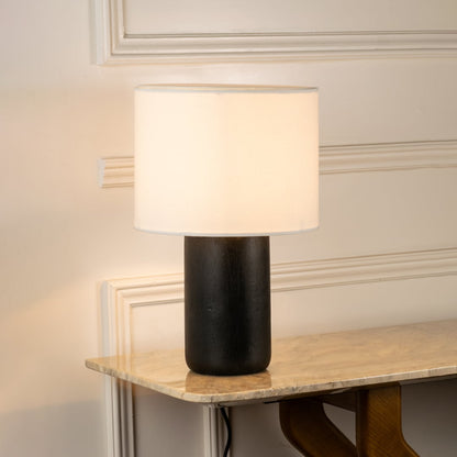 Black ceramic table lamp with white fabric shade casting warm ambient light for elegant bedside and living room decor.