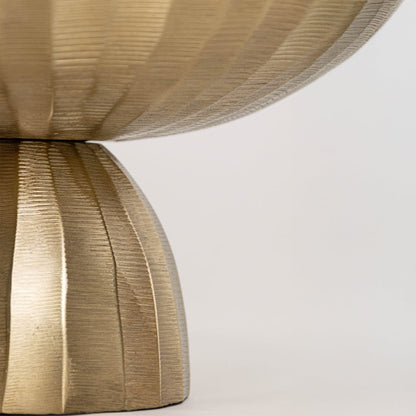 Close view of gold bowl showing detailed hammered interior and sculpted metal base with reflective textured finish