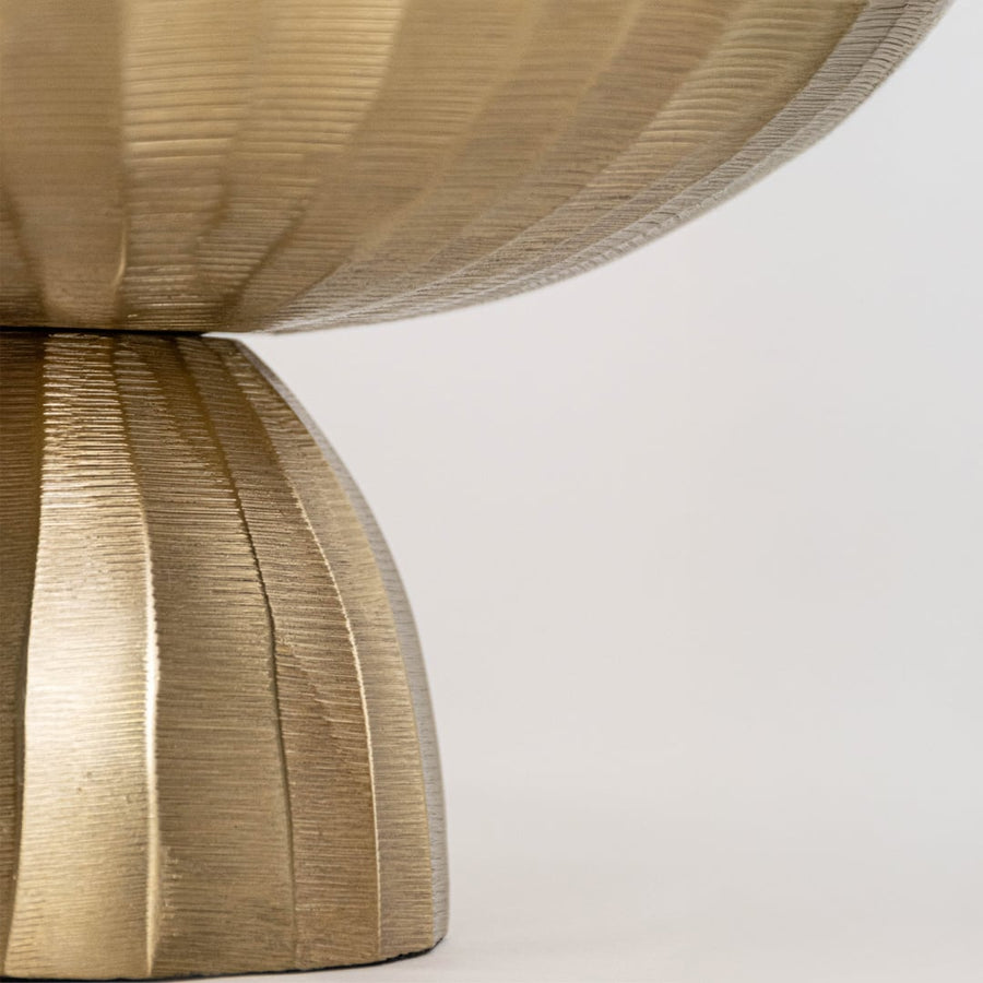 Close view of gold bowl showing detailed hammered interior and sculpted metal base with reflective textured finish