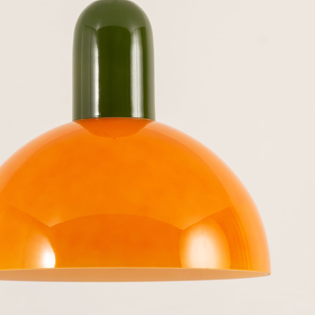 Closeup of orange and green dome pendant showing its polished finish and smooth curvature reflecting warm ambient light with a refined aesthetic.