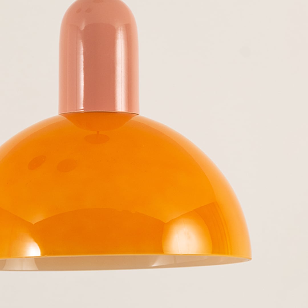 Closeup of orange and pink dome pendant showing its polished finish and smooth curvature reflecting warm ambient light with a refined aesthetic.