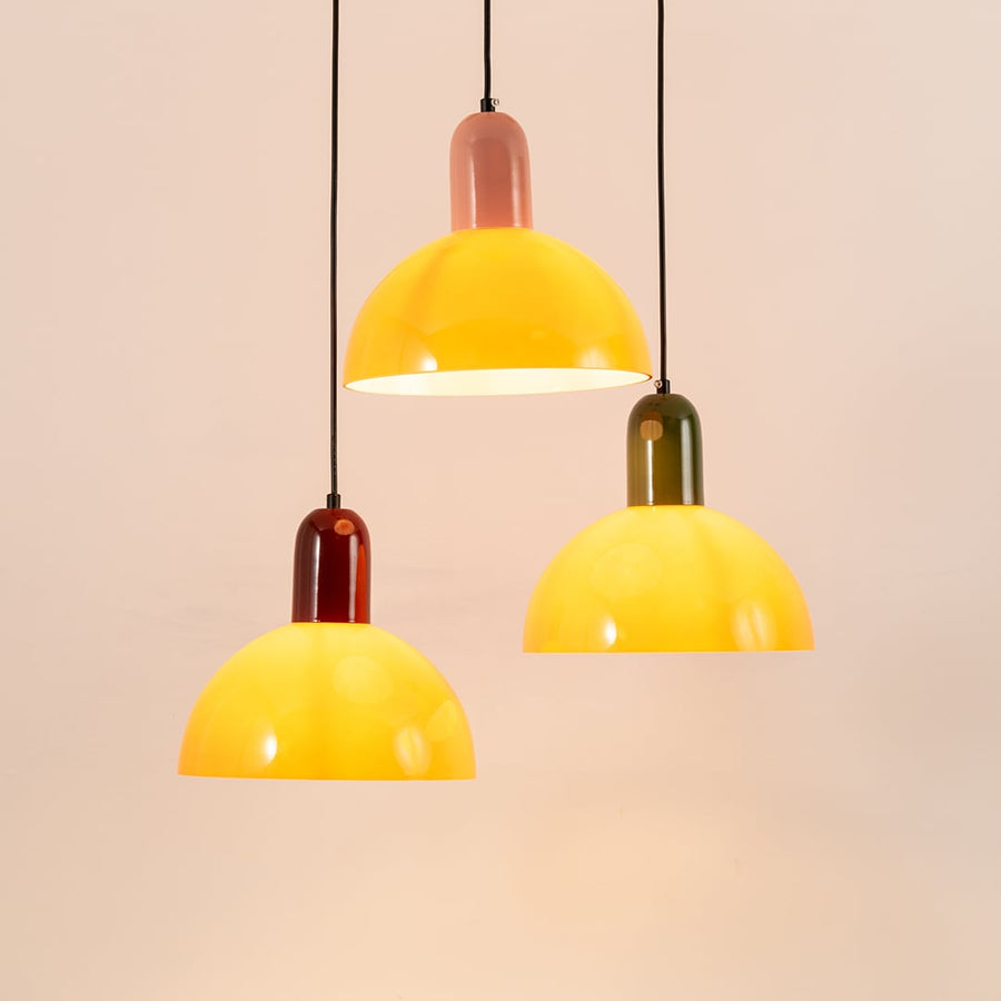 Set of three pendant lights with orange dome shades and colorful accents perfect for adding a modern and cheerful touch to home interiors.