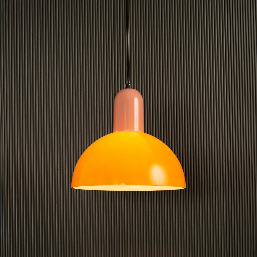 Bold orange and pink pendant lamp glowing beautifully on dark background highlighting its smooth finish and lively contemporary design.