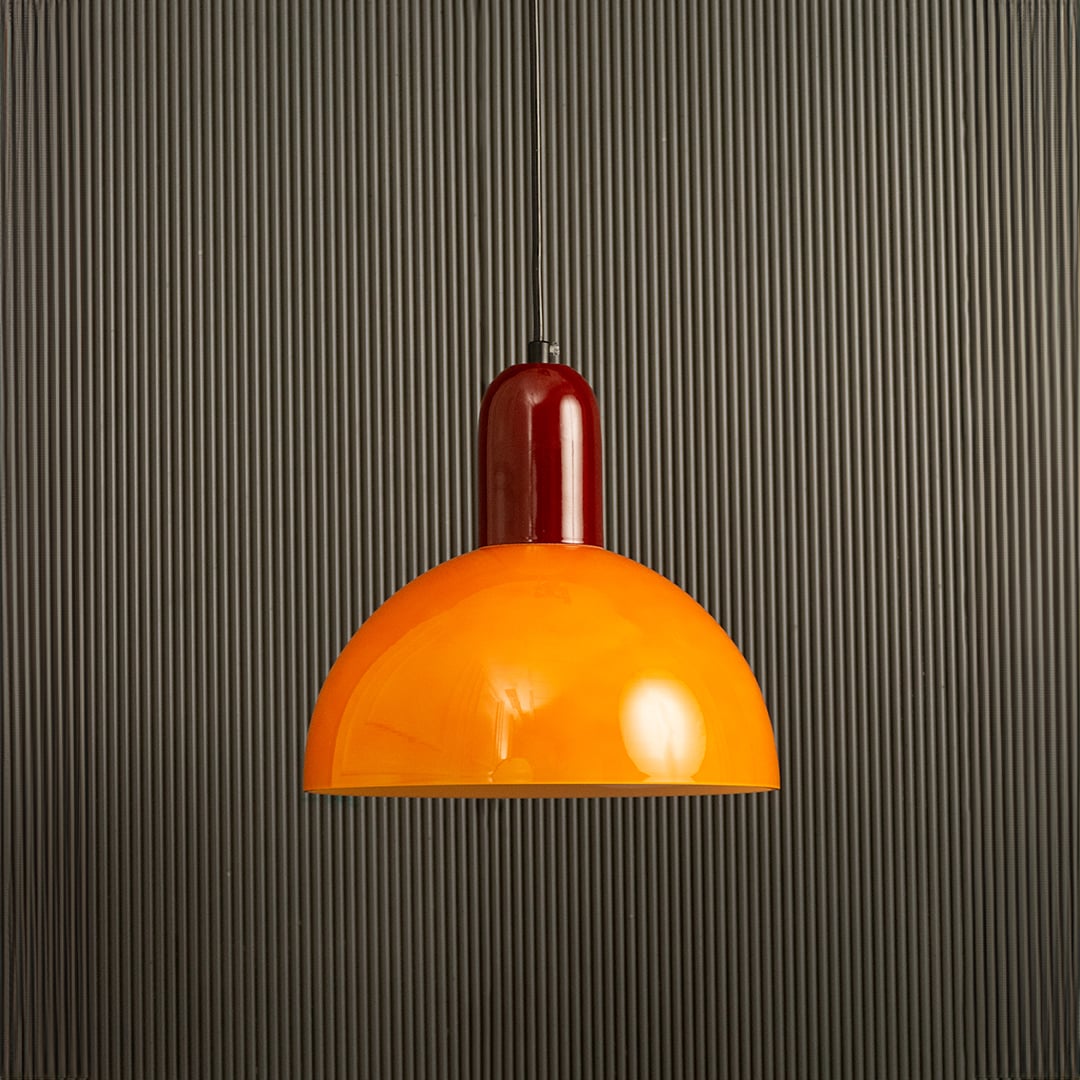 Unlit orange and red hanging pendant lamp on dark background emphasizing its sleek silhouette and playful yet elegant color contrast.