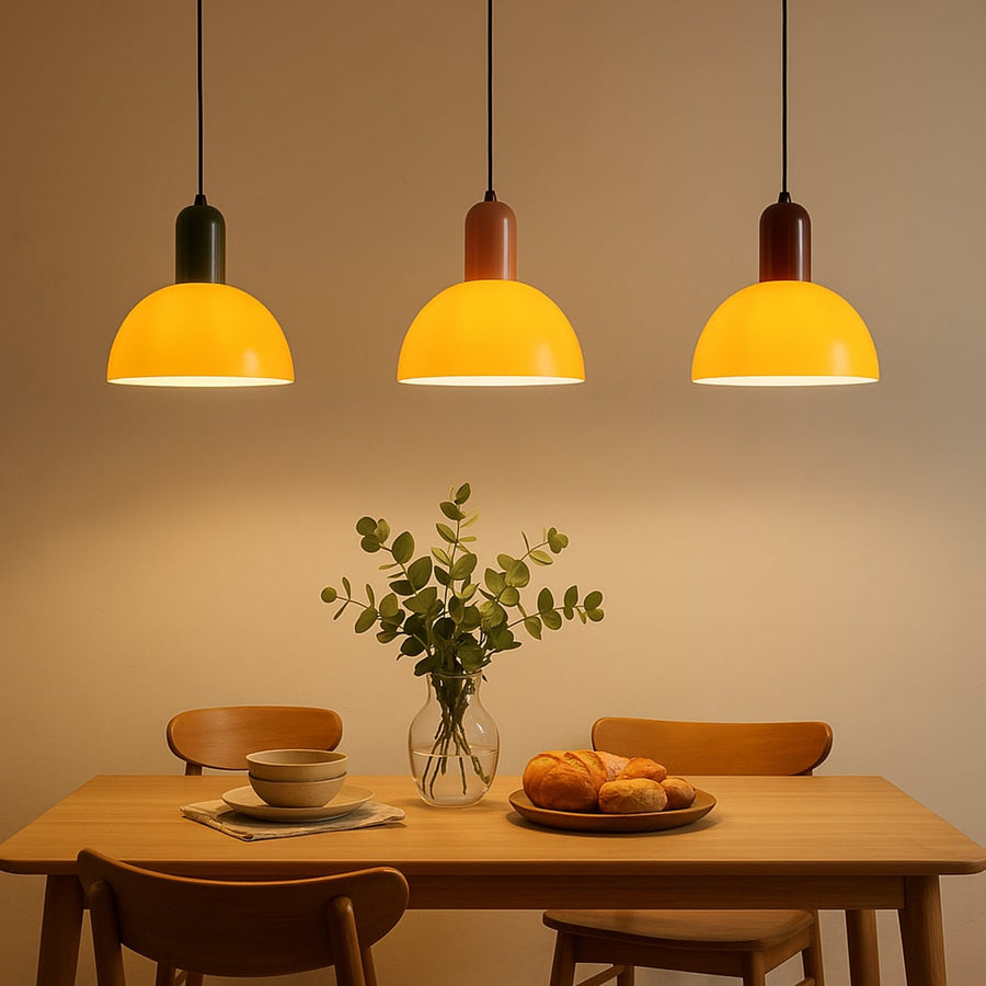 Yellow metal pendant lights above dining table creating warm ambient lighting in a modern dining room setting.