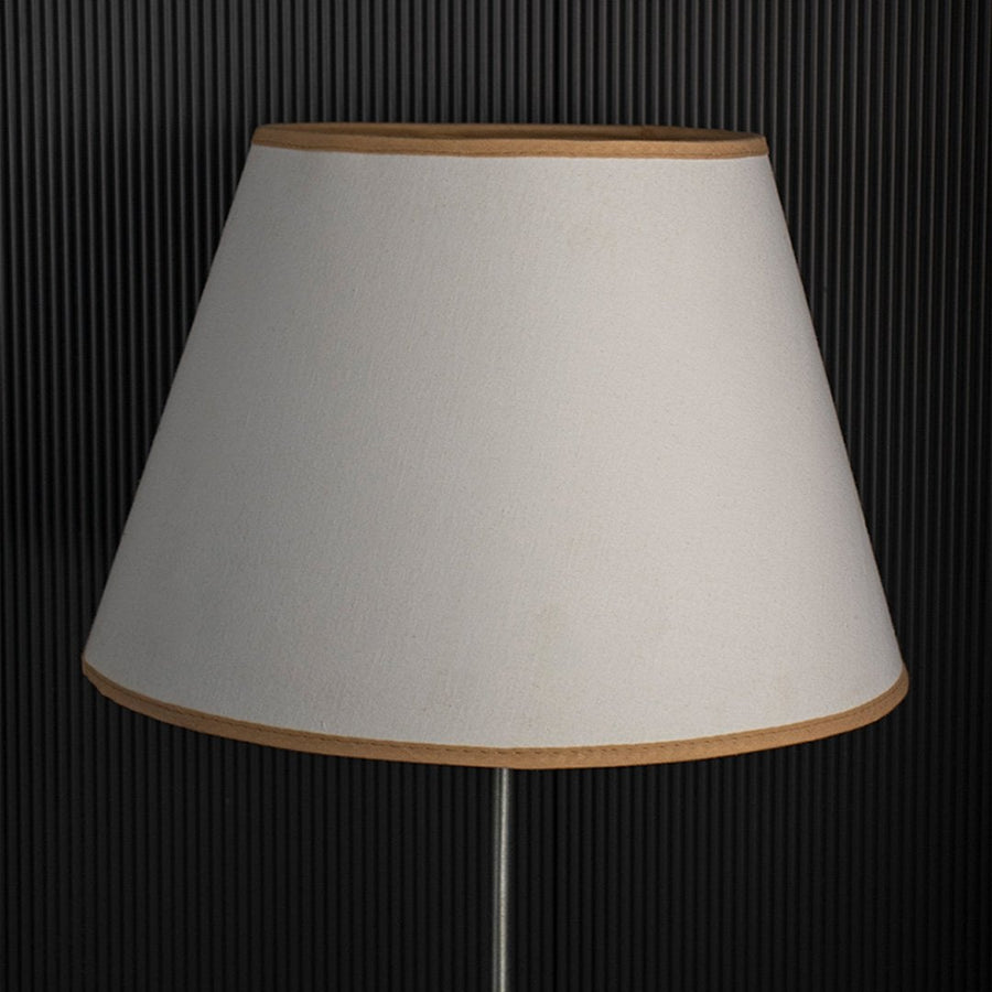 A classic tapered lampshade shown with light off black background highlighting its smooth beige fabric shape and clean stitched edges in a simple minimal style.