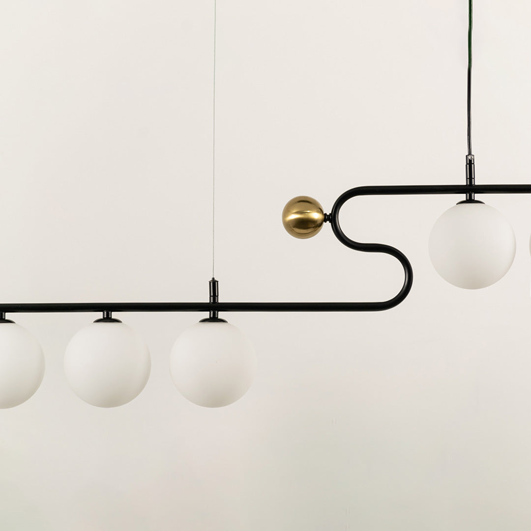 Gold and black metal chandelier with frosted glass globe shades showcasing elegant craftsmanship and modern lighting design.