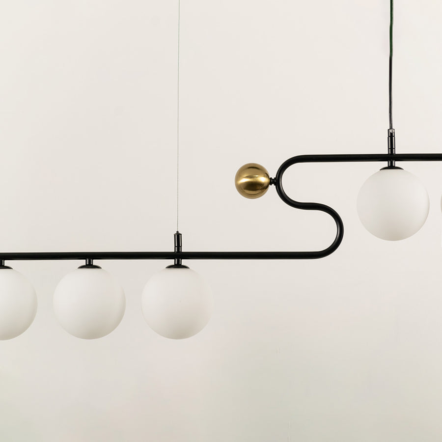 Gold and black metal chandelier with frosted glass globe shades showcasing elegant craftsmanship and modern lighting design.