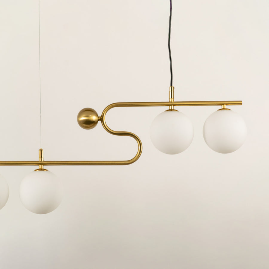 Gold metal chandelier with frosted glass globe shades showcasing elegant curved detailing and modern lighting design.