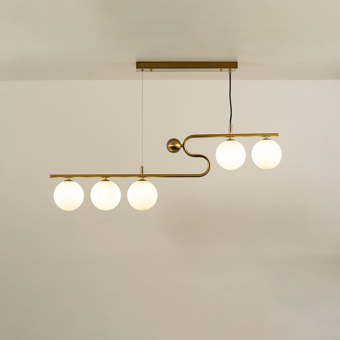 Gold asymmetrical ceiling light with white globe bulbs in a front view against a plain background with lights on perfect for modern lighting décor.