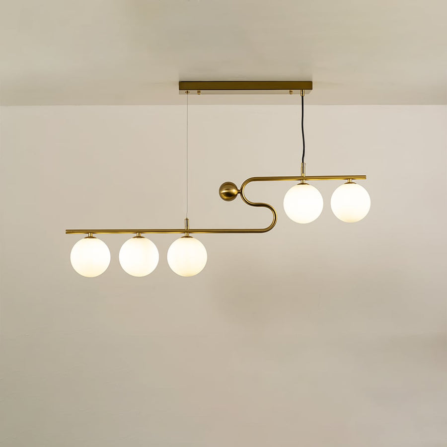 Gold asymmetrical ceiling light with white globe bulbs in a front view against a plain background with lights on perfect for modern lighting décor.