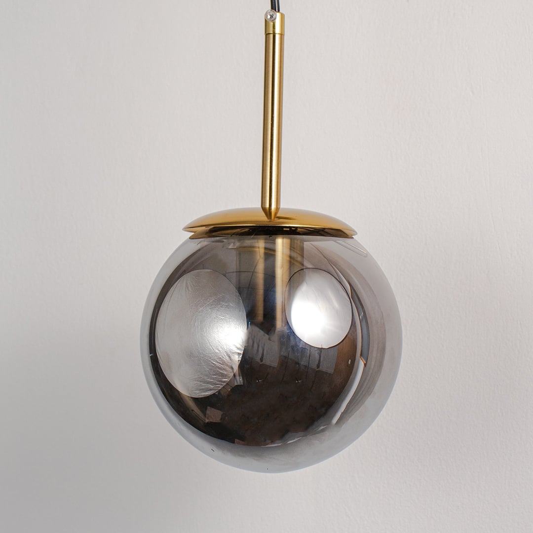 Closeup of smoked glass globe wall lamp with gold finish base showing elegant detail for stylish bedroom and hallway lighting.