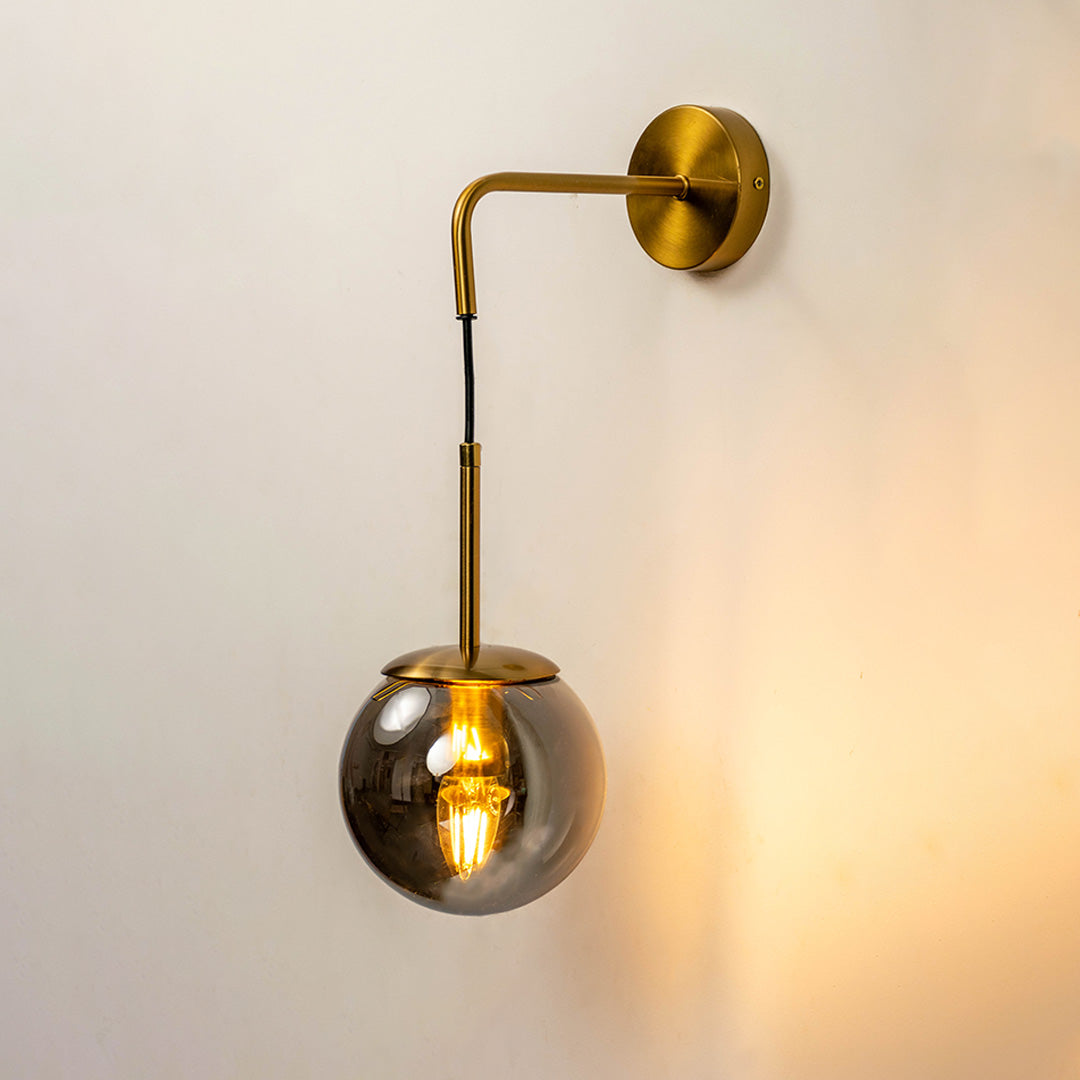Stylish hanging glass globe wall light with gold metal arm mounted on warm neutral wall background perfect for modern luxury interior decor.