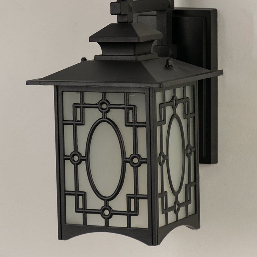 Closeup of black metal outdoor lantern highlighting its oval patterned frosted glass and intricate geometric frame for stylish exterior lighting.