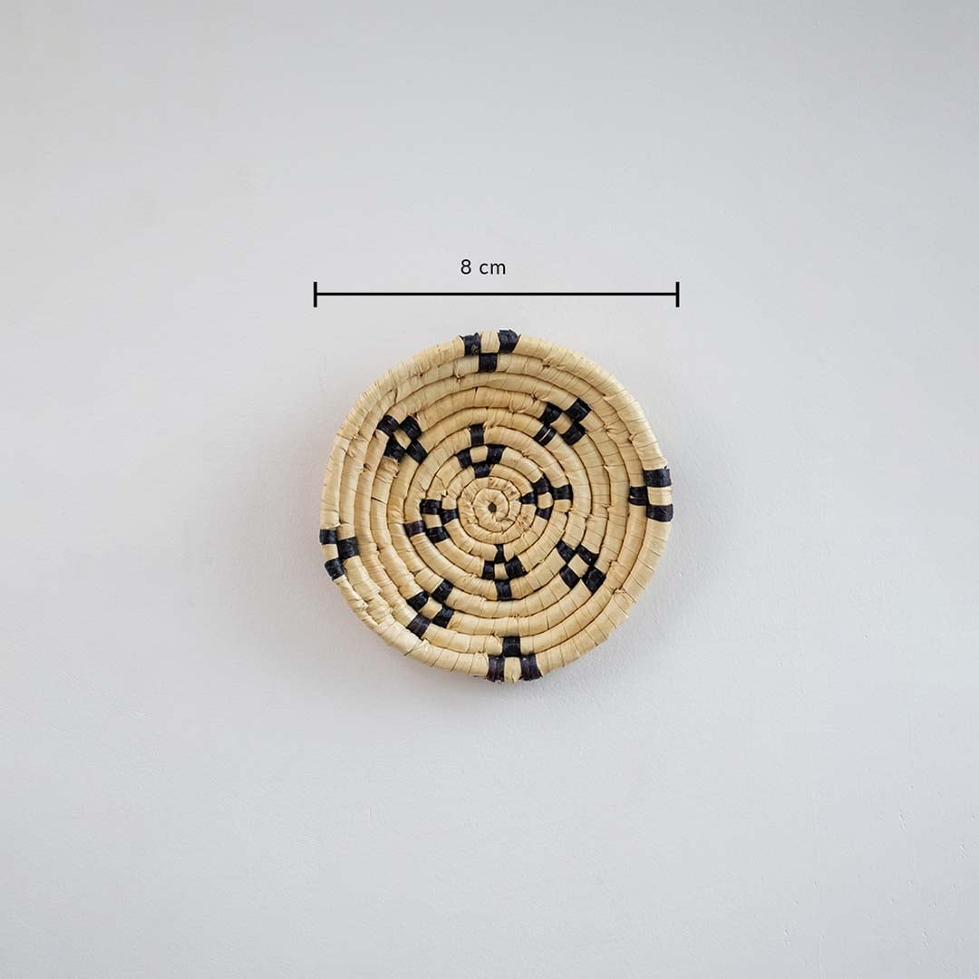 Handwoven round wall basket in natural and black tones showing approx 25 cm diameter for decorative wall placement reference.