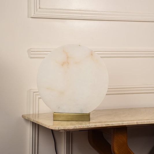 Round marble table lamp unlit on white background with metal base showcasing minimalist design perfect for elegant interior settings.