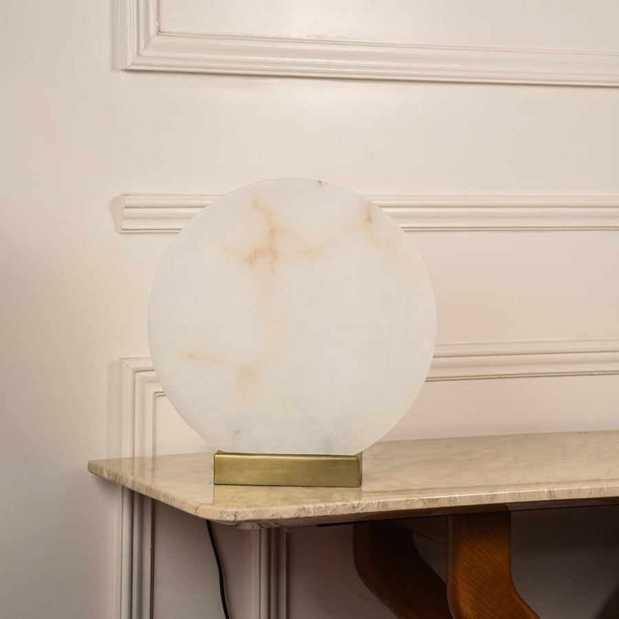 Round marble table lamp unlit on white background with metal base showcasing minimalist design perfect for elegant interior settings.