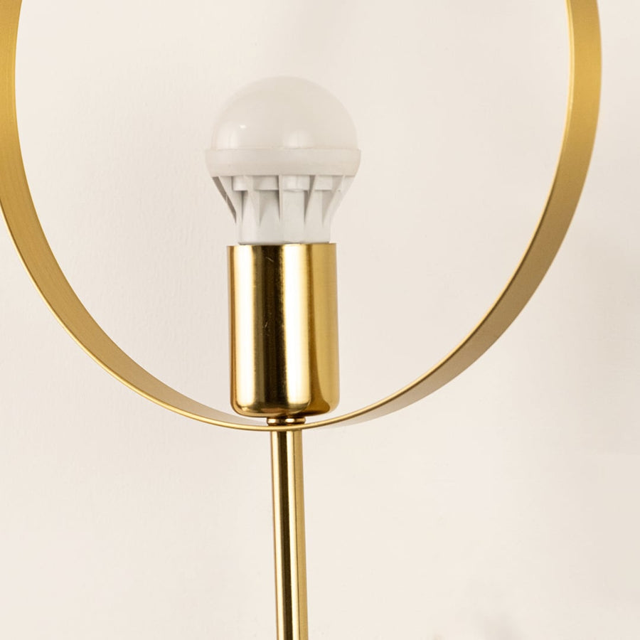 Closeup of brushed gold and clear glass wall light showing detailed metal finish and sleek hanging bulb design for modern interior decor.