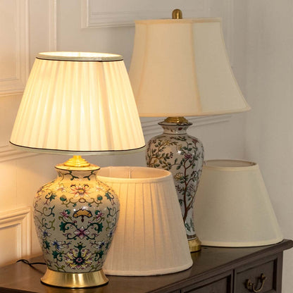 Table lamp with intricate floral ceramic base glowing softly beside another patterned lamp on a wooden console enhancing the cozy decor.