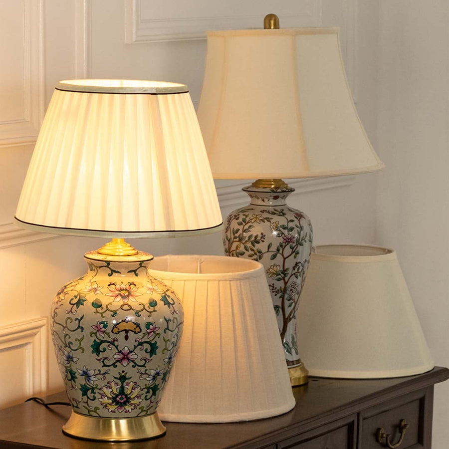 Table lamp with intricate floral ceramic base glowing softly beside another patterned lamp on a wooden console enhancing the cozy decor.