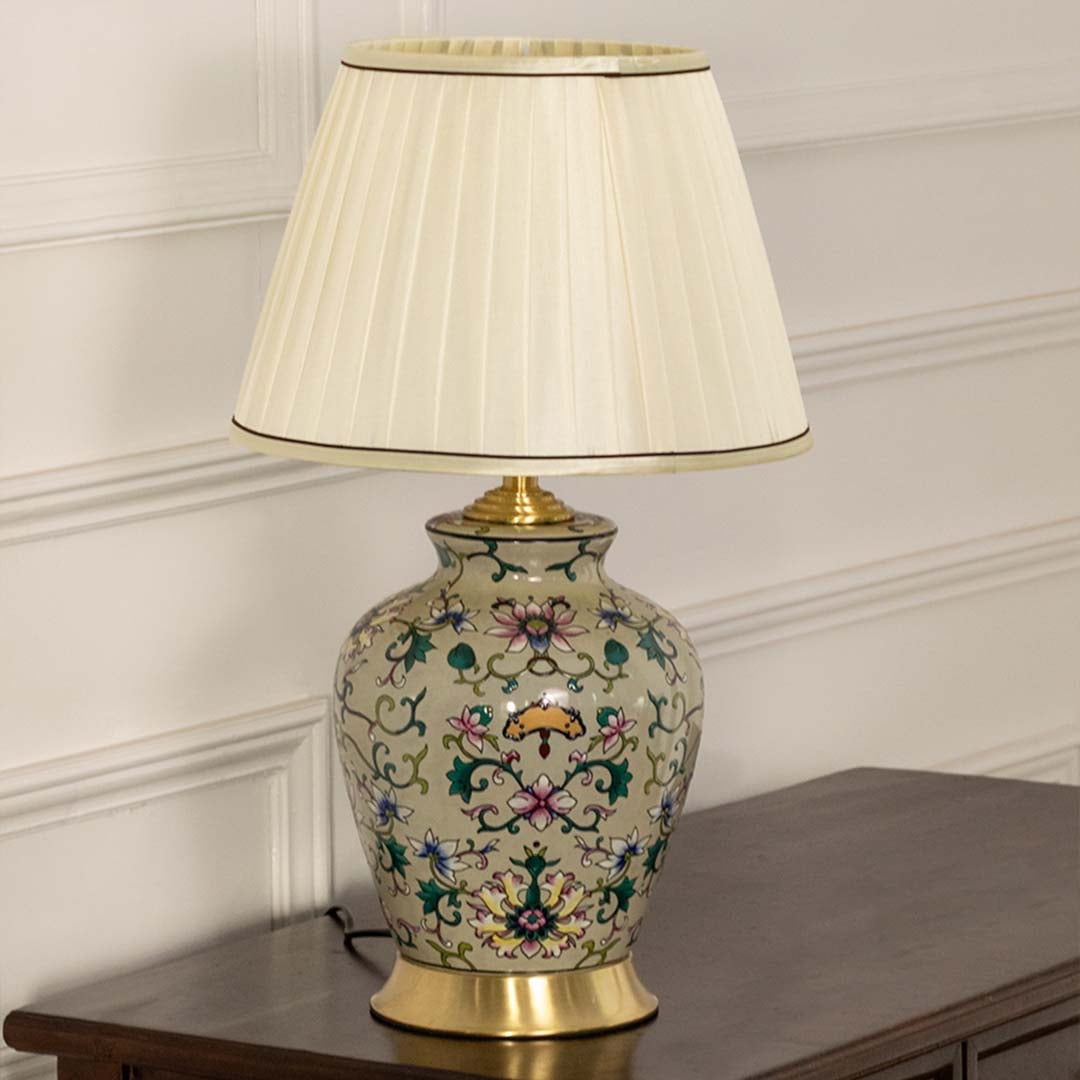 Cream floral ceramic lamp with gold accents and a pleated shade maintaining its artistic and decorative appeal even when unlit.