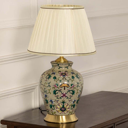 Cream floral ceramic lamp with gold accents and a pleated shade maintaining its artistic and decorative appeal even when unlit.