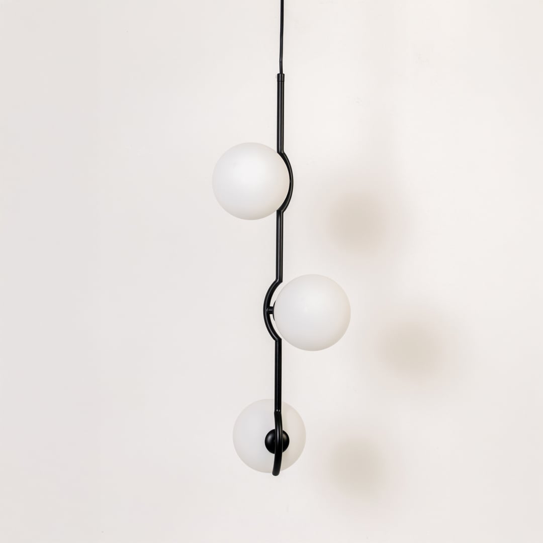Three-globe pendant light shown turned off on a white background highlighting its frosted round shades and modern black vertical structure.