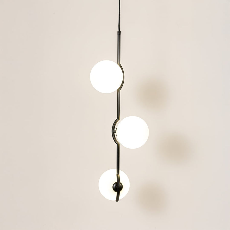 Elegant three-globe pendant light glowing softly on a clean white background featuring a sleek black frame and evenly spaced round shades.