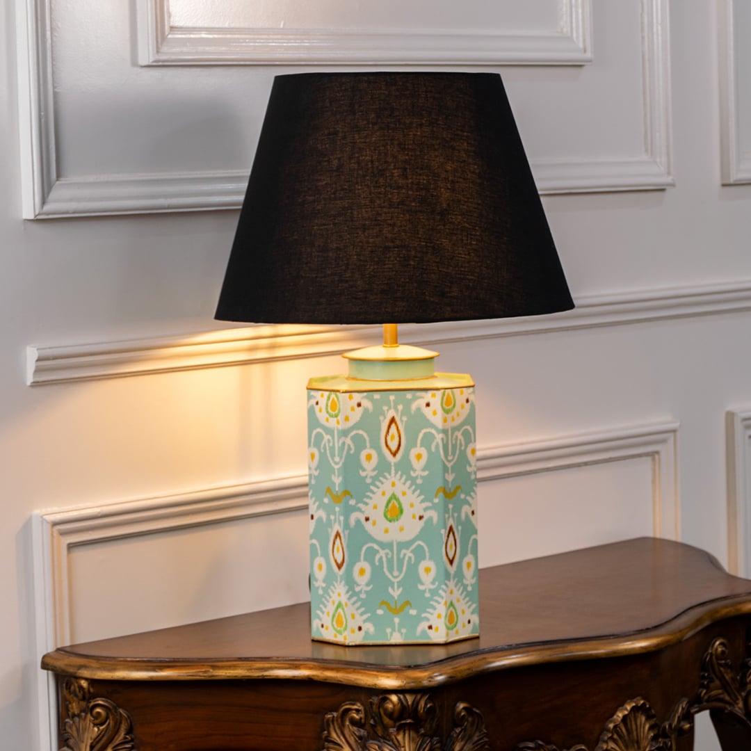 Stylish table lamp with black shade and pastel blue ceramic base adorned with symmetrical motifs and gold accents for bedside decor.