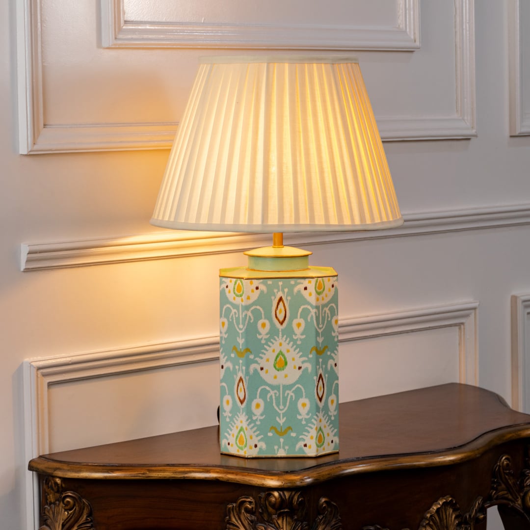Stylish table lamp with pleated white shade and light blue ceramic base showcasing symmetrical motifs and refined gold detailing.
