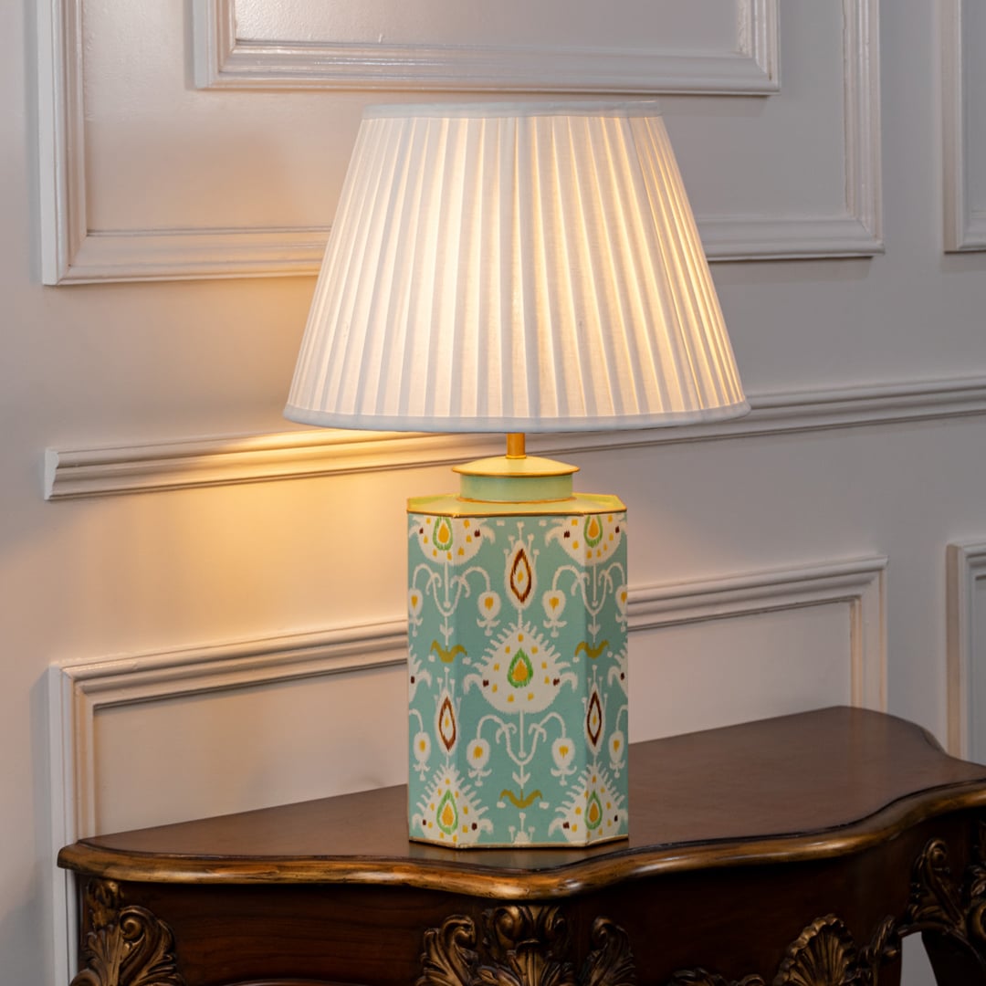 Decorative table lamp with white pleated shade and mint green patterned ceramic base finished with subtle gold accents.
