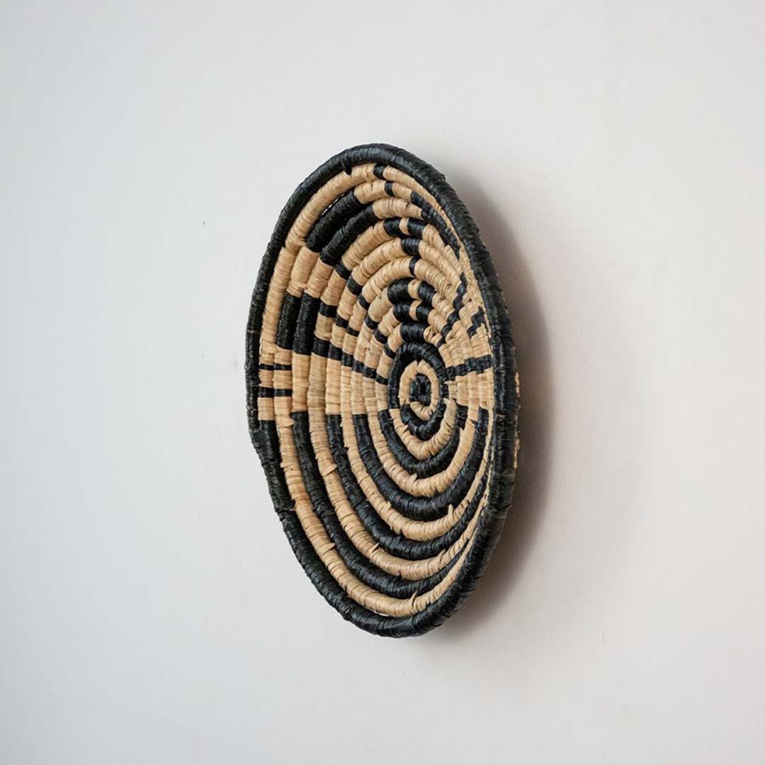 Handwoven wicker wall decor plate side view in natural beige and black design showing thickness and artisan weaving detail.