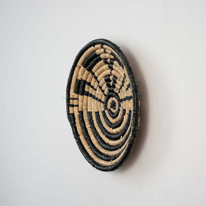Handwoven wicker wall decor plate side view in natural beige and black design showing thickness and artisan weaving detail.