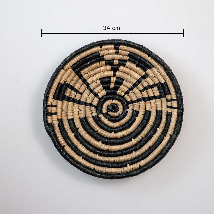 Handwoven wicker wall decor plate 34 cm round beige and black design light off white background showing product dimensions.