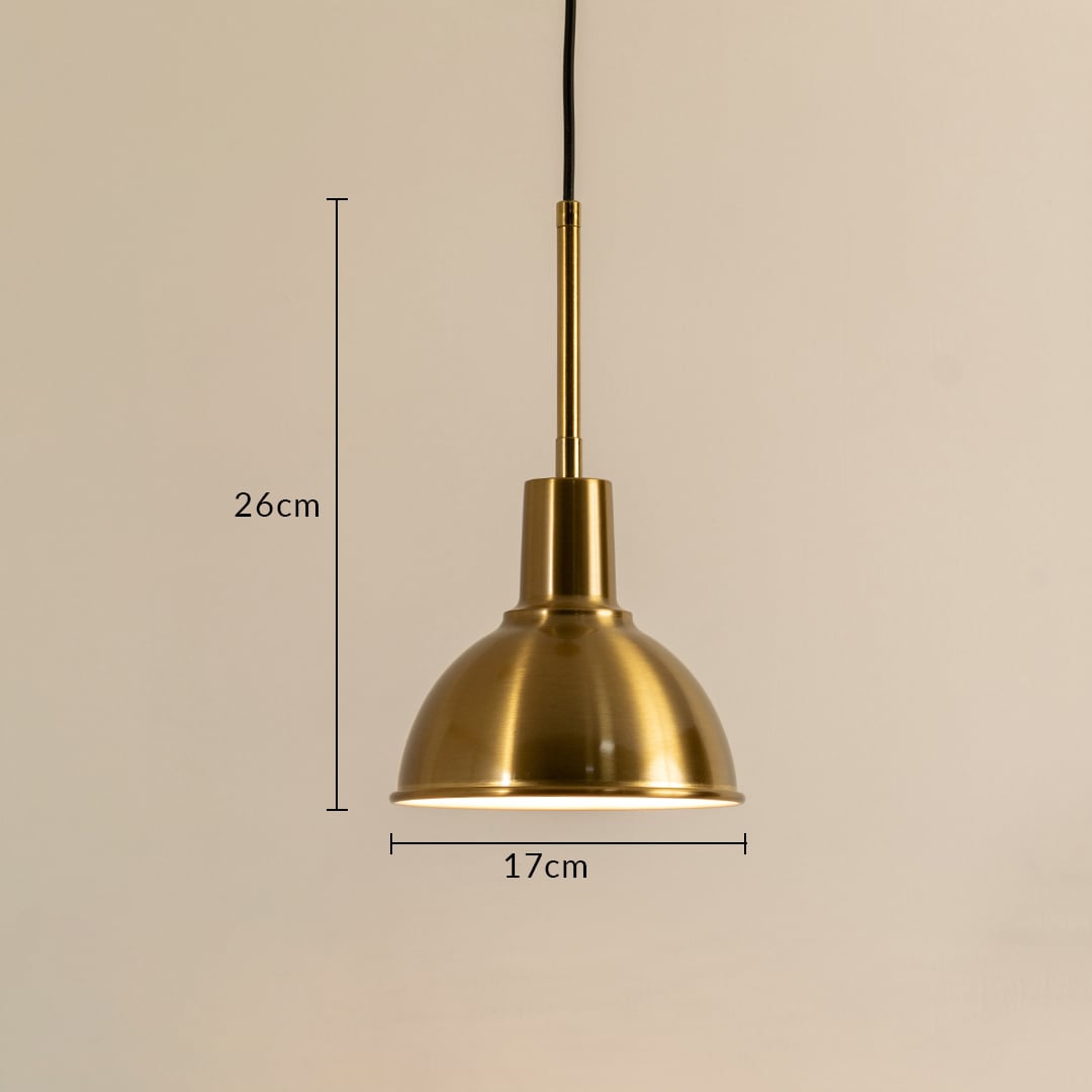 A metal dome pendant light measuring 26 cm height and 17 cm width shining warmly against a smooth beige backdrop providing classic soft lighting and elegant interior décor.