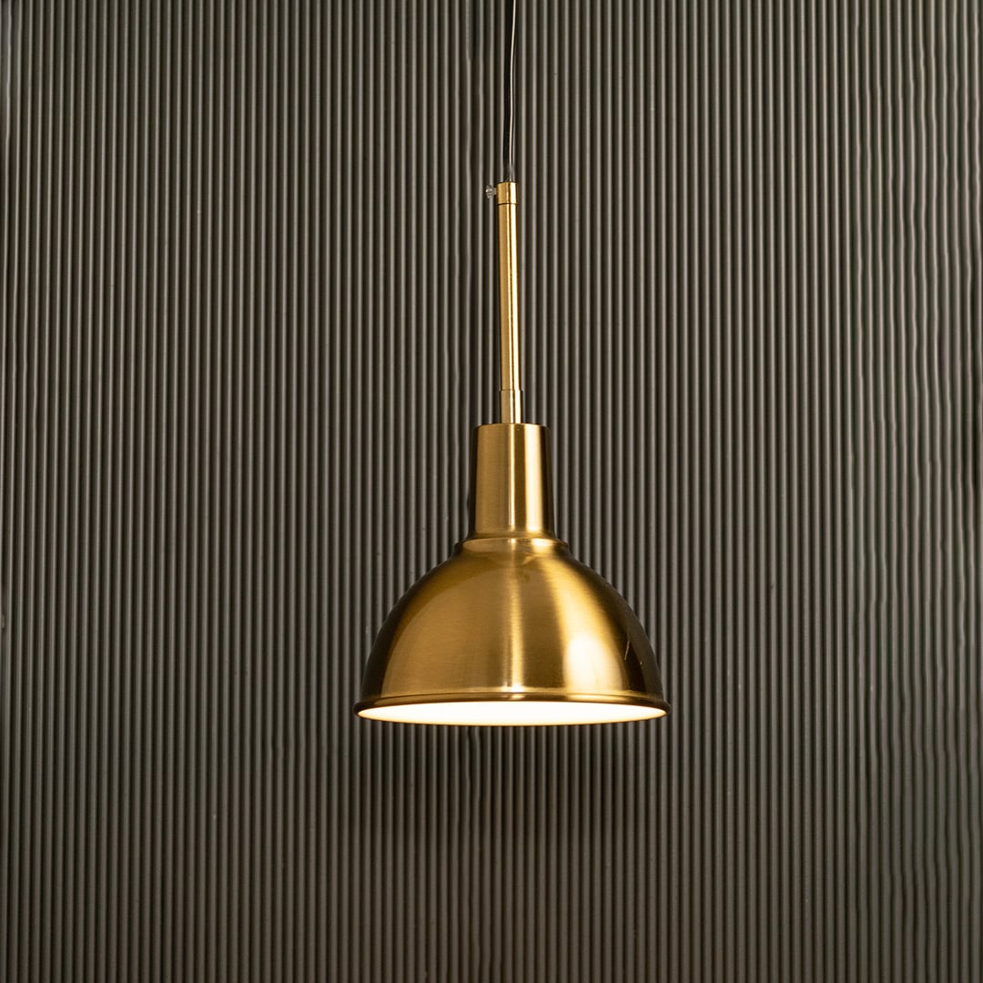 A metal dome pendant light shining warmly against a ribbed dark backdrop offering classic soft illumination and sophisticated modern interior décor.