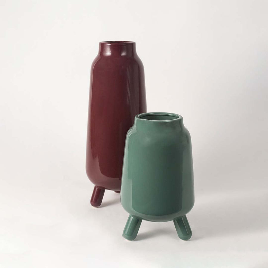 A minimal product display featuring the green tripod vase on a white backdrop highlighting its rounded form and modern elevated base.