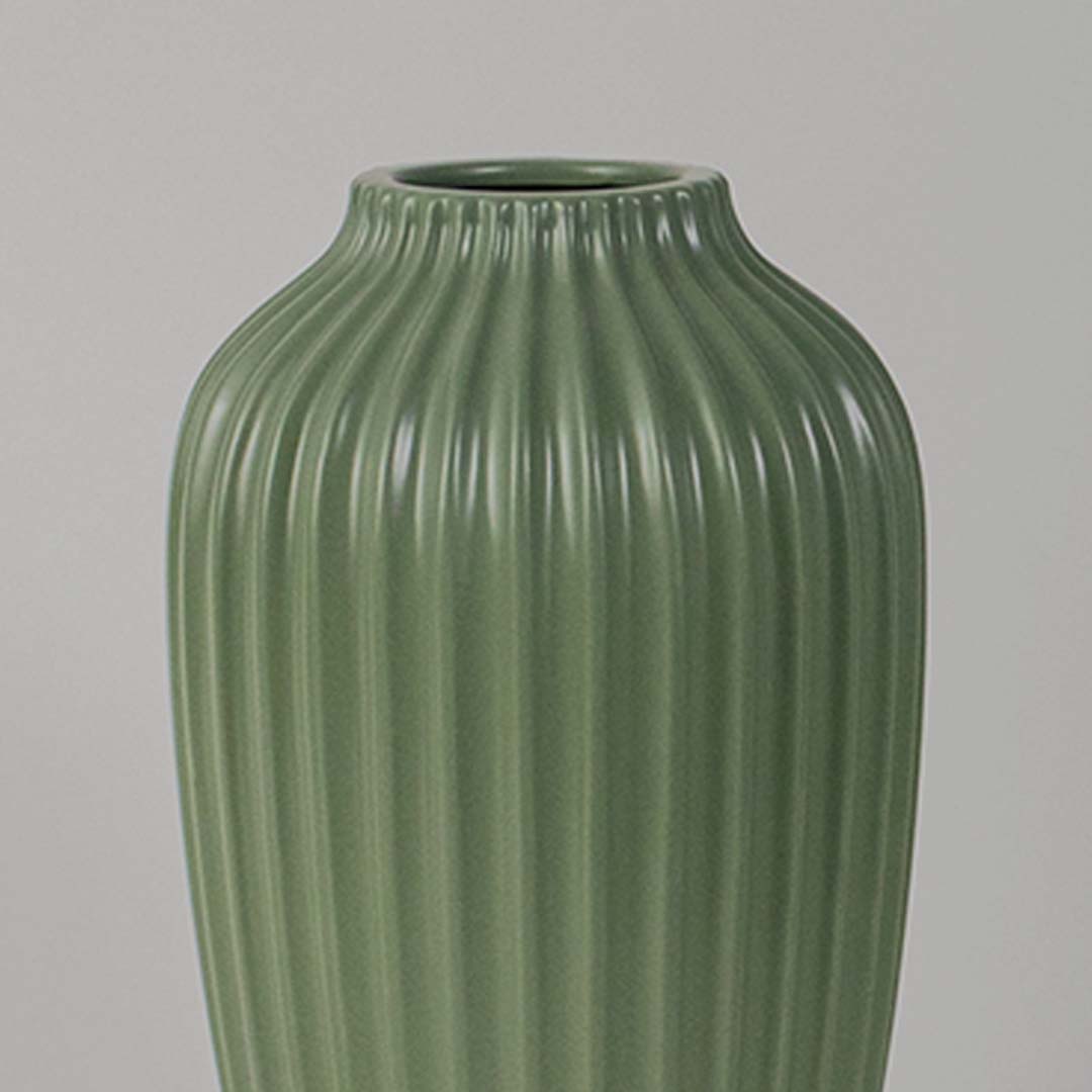 Closeup view of the green ribbed vase showing the detailed vertical grooves and smooth ceramic finish with clear focus on texture and shape.