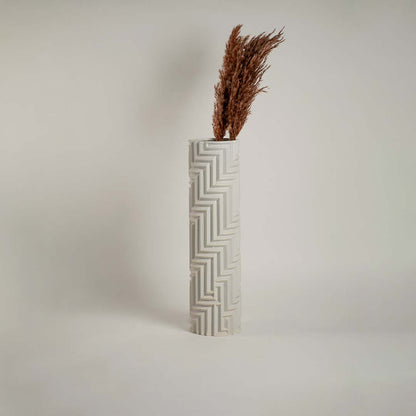 White ceramic vase with geometric detailing against a clean white backdrop emphasizing its refined craftsmanship.
