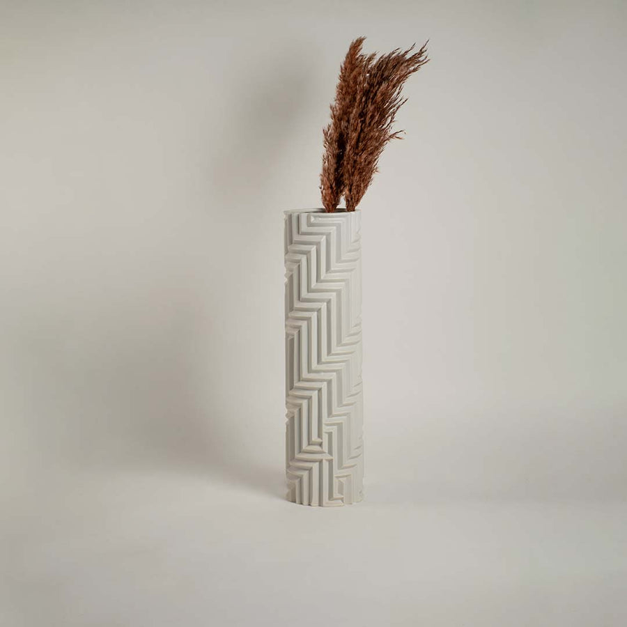 White ceramic vase with geometric detailing against a clean white backdrop emphasizing its refined craftsmanship.