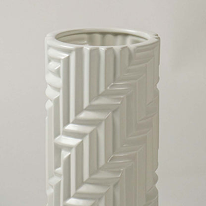 A detailed closeup of the white textured vase showing its raised geometric pattern and smooth cylindrical shape in a soft light background.