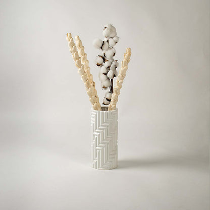 A stylish white textured vase showcased in a minimal lifestyle setup with soft shadows enhancing its sculpted modern design.