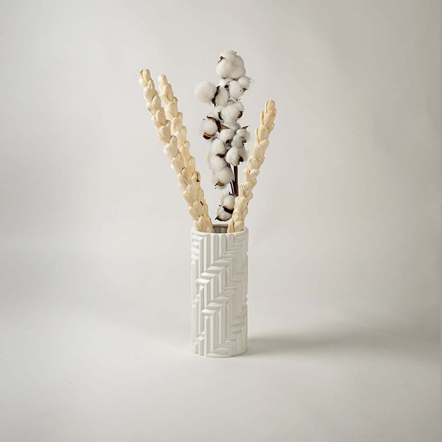 A stylish white textured vase showcased in a minimal lifestyle setup with soft shadows enhancing its sculpted modern design.