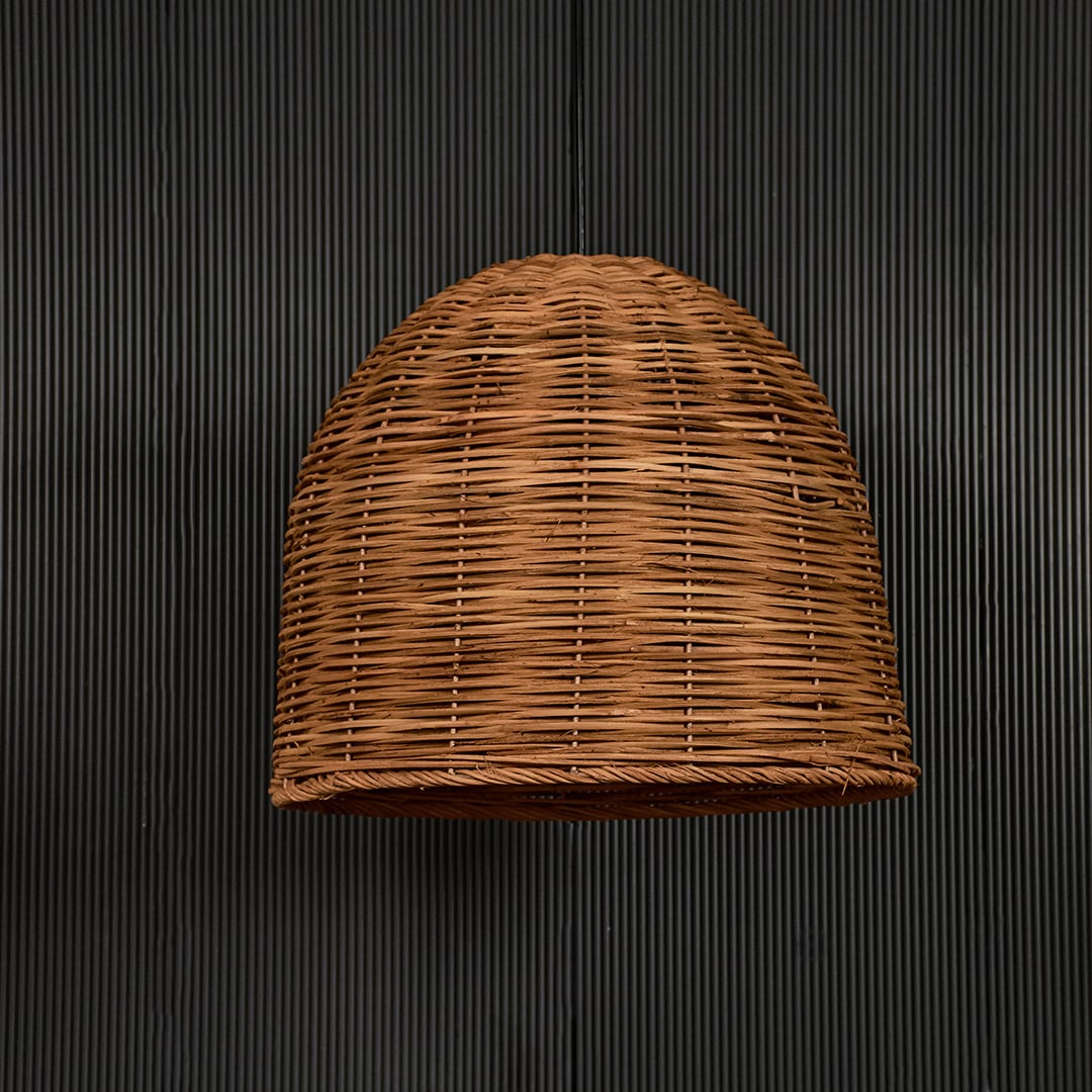 Natural rattan pendant light on black background highlighting its handcrafted texture and shape.