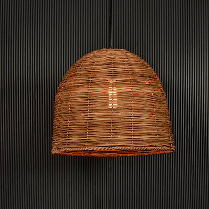 Rattan pendant light glowing warmly on black background creating an inviting rustic aesthetic.
