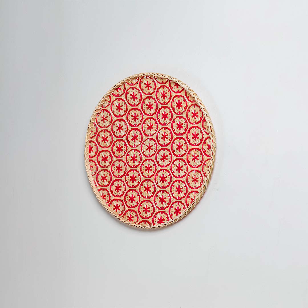 Side view of woven bamboo basket tray showing depth and handcrafted construction with red geometric floral pattern detail.