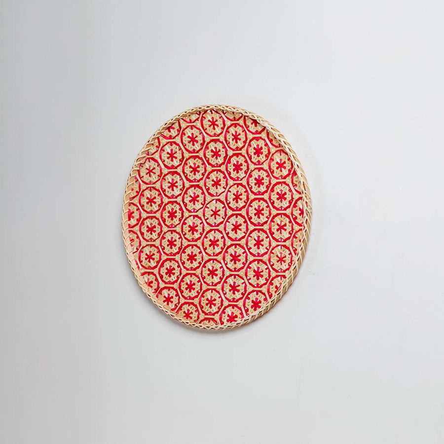 Side view of woven bamboo basket tray showing depth and handcrafted construction with red geometric floral pattern detail.